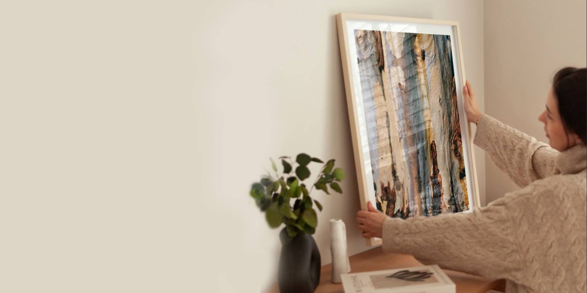 Person adjusting a framed picture on a wall