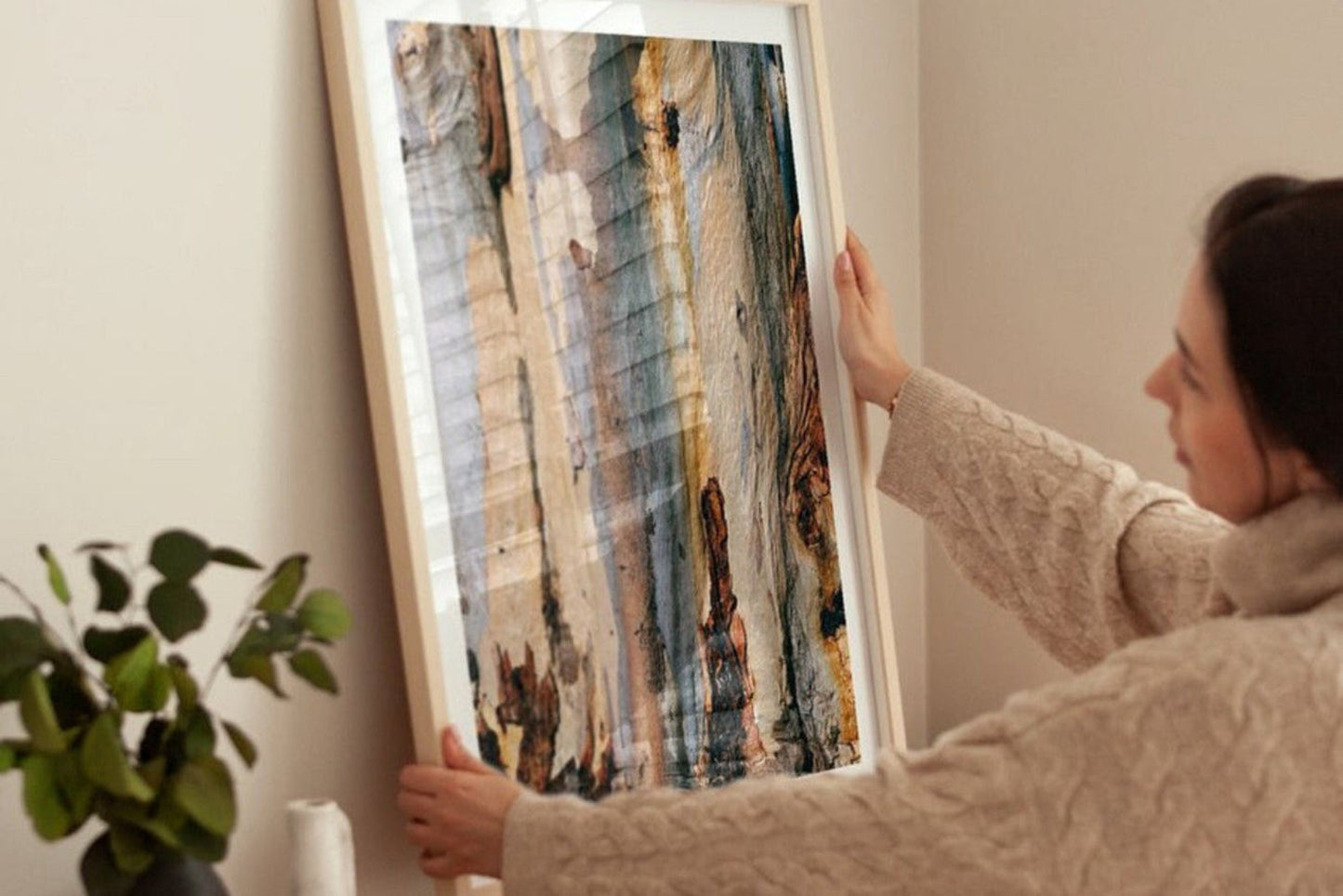 Person hanging a framed artwork on a wall